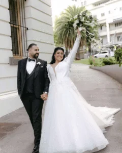 joyful bride raising her bouquet walking with groom on a Melbourne city street just married – Gee What a Wedding