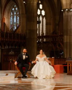 Interstate couple bride and groom seated inside St Patrick's Cathedral Melbourne during their wedding ceremony – Gee What a Wedding