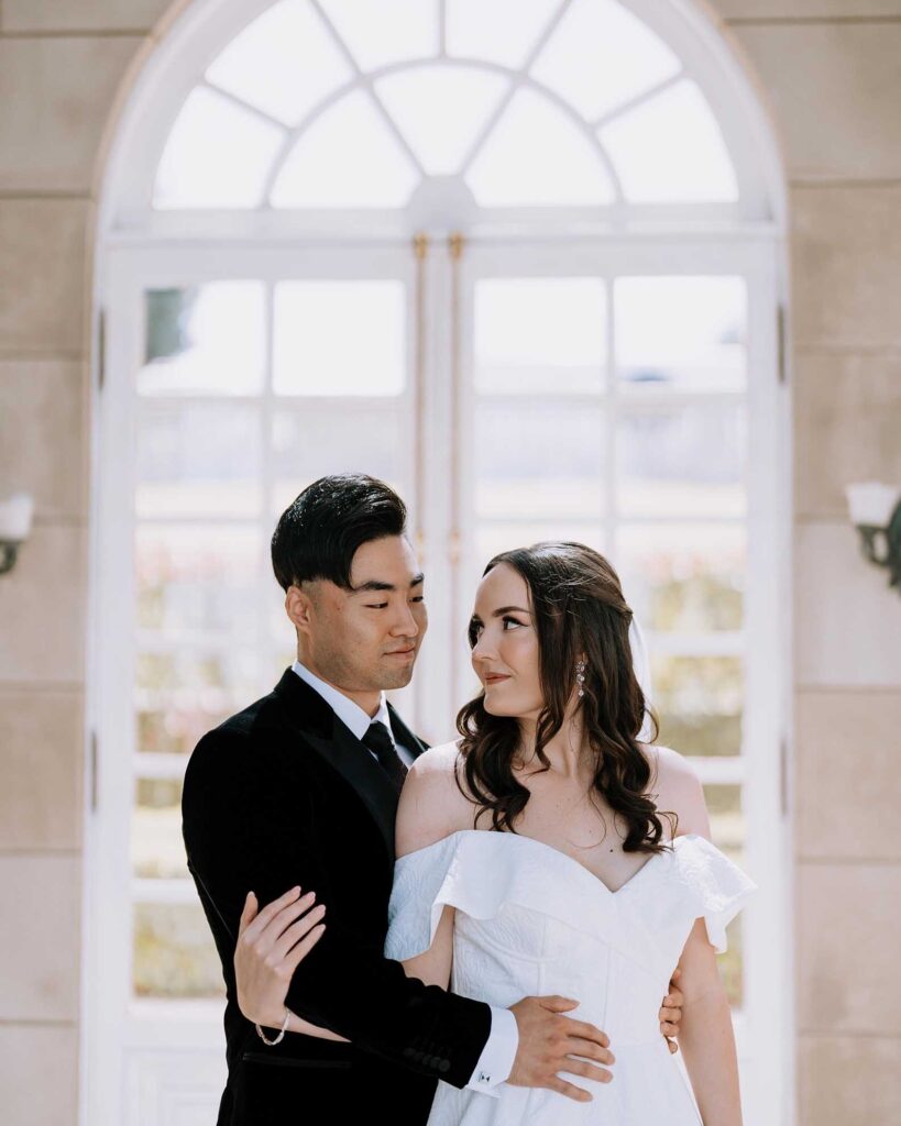 Melbourne wedding planner Gee Tankir's couple portrait beneath the arched doorway at Campbell Point House, a prestigious French chateau-style estate on the Bellarine Peninsula, full wedding planning services